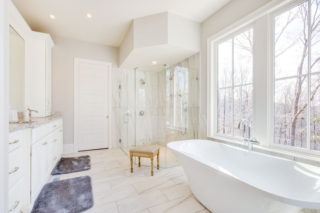 Remodeled bathroom with a freestanding soaking tub, marble tiled shower and a white vanity