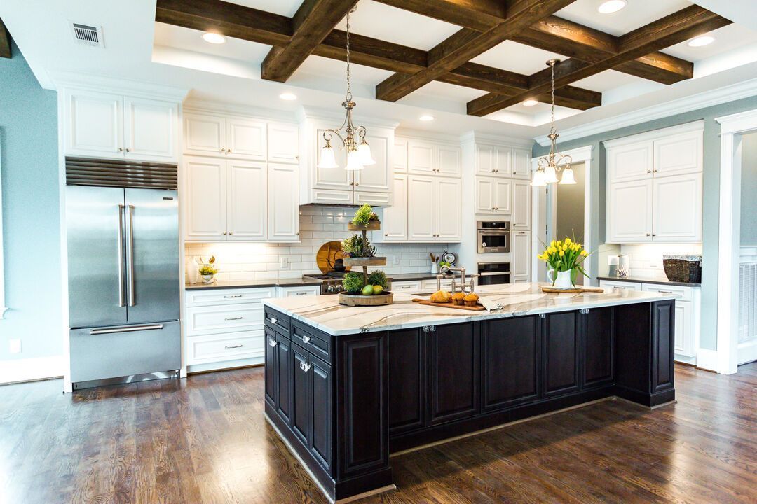 Open plan interior remodel with white cabinetry, a dark stained island and exposed ceiling beams